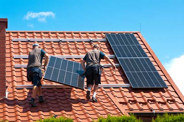 2 men fitting solar panels to a roof